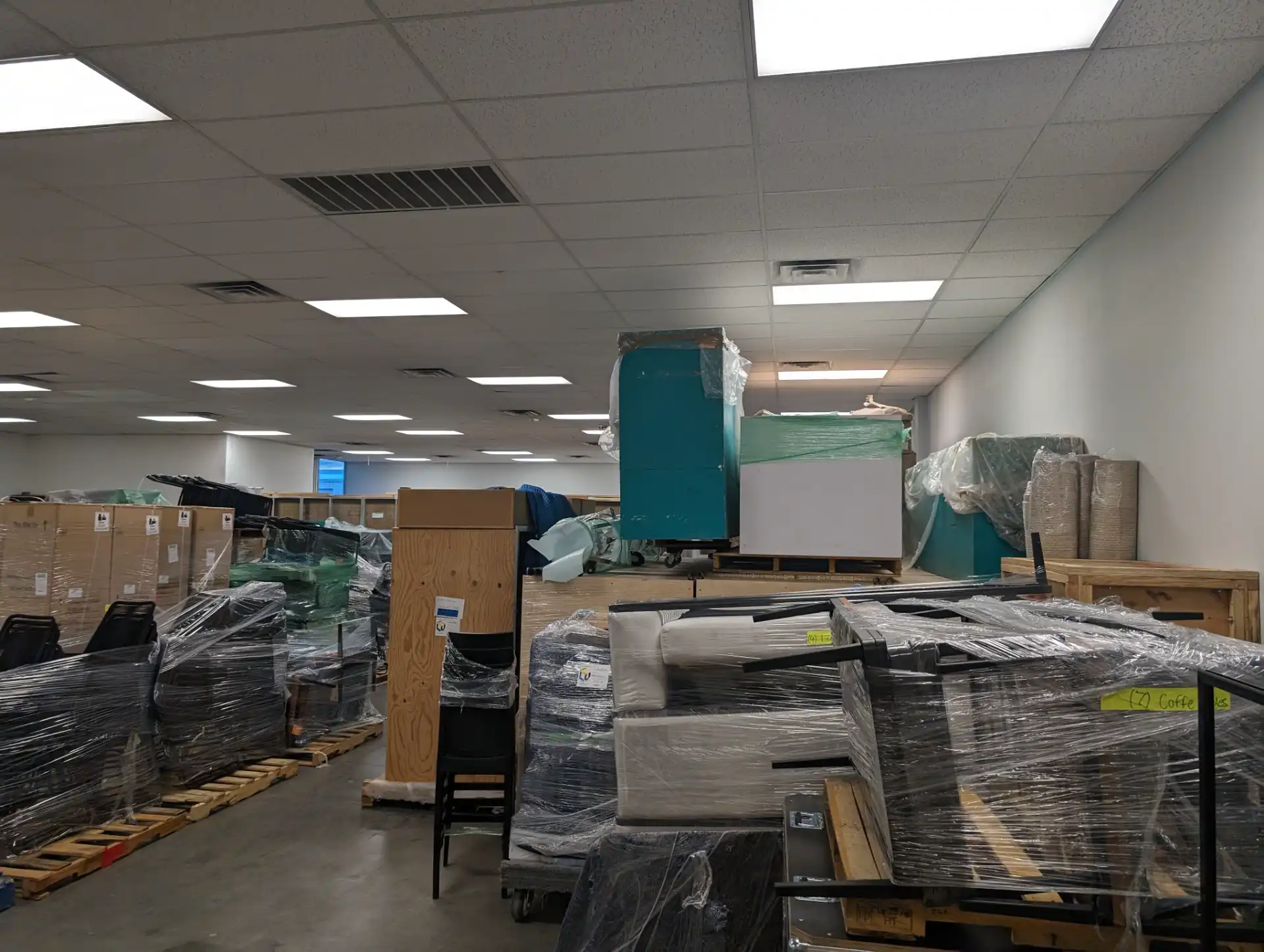 Warehouse floor stacked with wrapped furniture and crated items